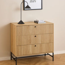 Load image into Gallery viewer, Wooden cabinet with black legs and a lamp on top against a beige wall.