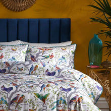 Load image into Gallery viewer, Bed with colorful bird pattern bedding against a yellow wall with a blue headboard.