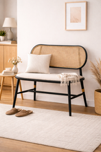 Load image into Gallery viewer, Wicker bench with black frame and white cushion in a room with wooden floor and white walls.