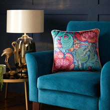 Load image into Gallery viewer, Blue armchair with a colorful patterned pillow next to a lamp and decorative flamingo on a side table.