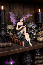 Load image into Gallery viewer, Gothic-style figurine with bat wings reading a book surrounded by skulls, candles, and potion bottles on a wooden shelf.