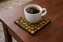 Load image into Gallery viewer, White mug of coffee on a decorative coaster on a wooden table