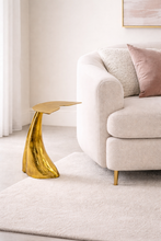 Load image into Gallery viewer, Gold side table next to a white sofa with pink cushions in a modern living room.