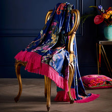 Load image into Gallery viewer, Decorative chair with a floral blanket and pink fringes against a dark wall.