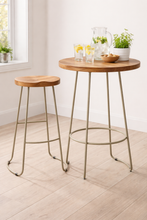 Load image into Gallery viewer, Wooden bar table with metal legs and two stools in a bright room.