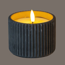 Load image into Gallery viewer, Black ribbed candle holder with a lit candle on a gray background
