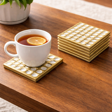 Load image into Gallery viewer, White mug with tea and an orange slice on a gold coaster, with additional coasters stacked in the background.