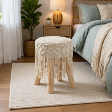 Load image into Gallery viewer, Macrame-styled stool in a bedroom setting with a bed and nightstand.