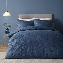 Load image into Gallery viewer, Navy blue textured bedding set on a bed against a dark blue wall with a side table and lamp.
