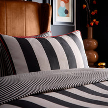 Load image into Gallery viewer, Striped pillow and blanket on a bed with a brown chair and abstract art in the background.
