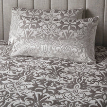 Load image into Gallery viewer, Patterned bedding set with decorative pillows on a bed.
