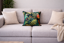 Load image into Gallery viewer, Gray sofa with decorative pillows featuring parrots and leaves, and a beige blanket.
