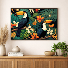Load image into Gallery viewer, Framed artwork of toucans and tropical foliage on a wall above a wooden cabinet with decor items.

