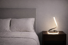 Load image into Gallery viewer, Bedroom with a bed and a nightstand with a lamp.
