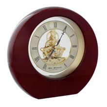 Load image into Gallery viewer, A round, glossy dark red wooden table clock with a visible gold-toned mechanical gear system through the center dial, Roman numerals, and black hands on a white background.
