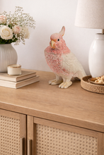 Load image into Gallery viewer, Decorative parrot figurine on a wooden surface with books, flowers, and a lamp in the background.
