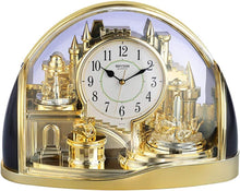 Load image into Gallery viewer, A Rhythm Clock decorative table clock with a gold-colored castle and architectural model design inside a clear domed case, featuring a white clock face with black numbers and hands.
