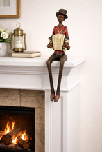 Load image into Gallery viewer, Statue of a person playing an accordion on a mantelpiece with a fireplace in the background.
