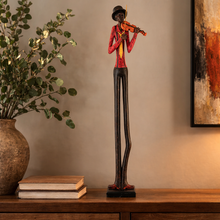 Load image into Gallery viewer, Statue of a musician playing a violin on a wooden surface with books and a plant.
