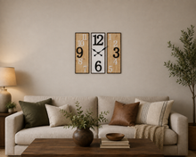 Load image into Gallery viewer, A modern three-panel wall clock with a retro numeric design hangs above a beige sofa in a styled living room. The clock features wood-grain panels on the left and right with black numbers, and a central white panel with black numbers and hands.
